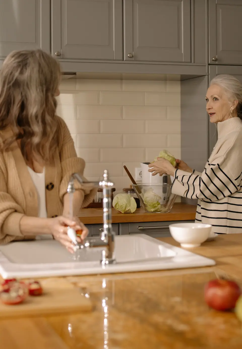 Una signora anziana e una donna preparano l'insalata insieme in cucina