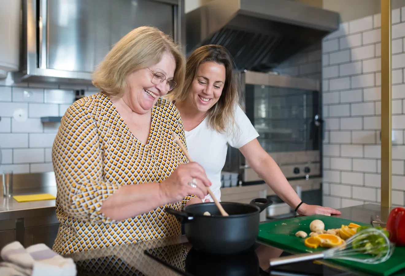 Due donne cucinano insieme ai fornelli, l’anziana mescola nella pentola