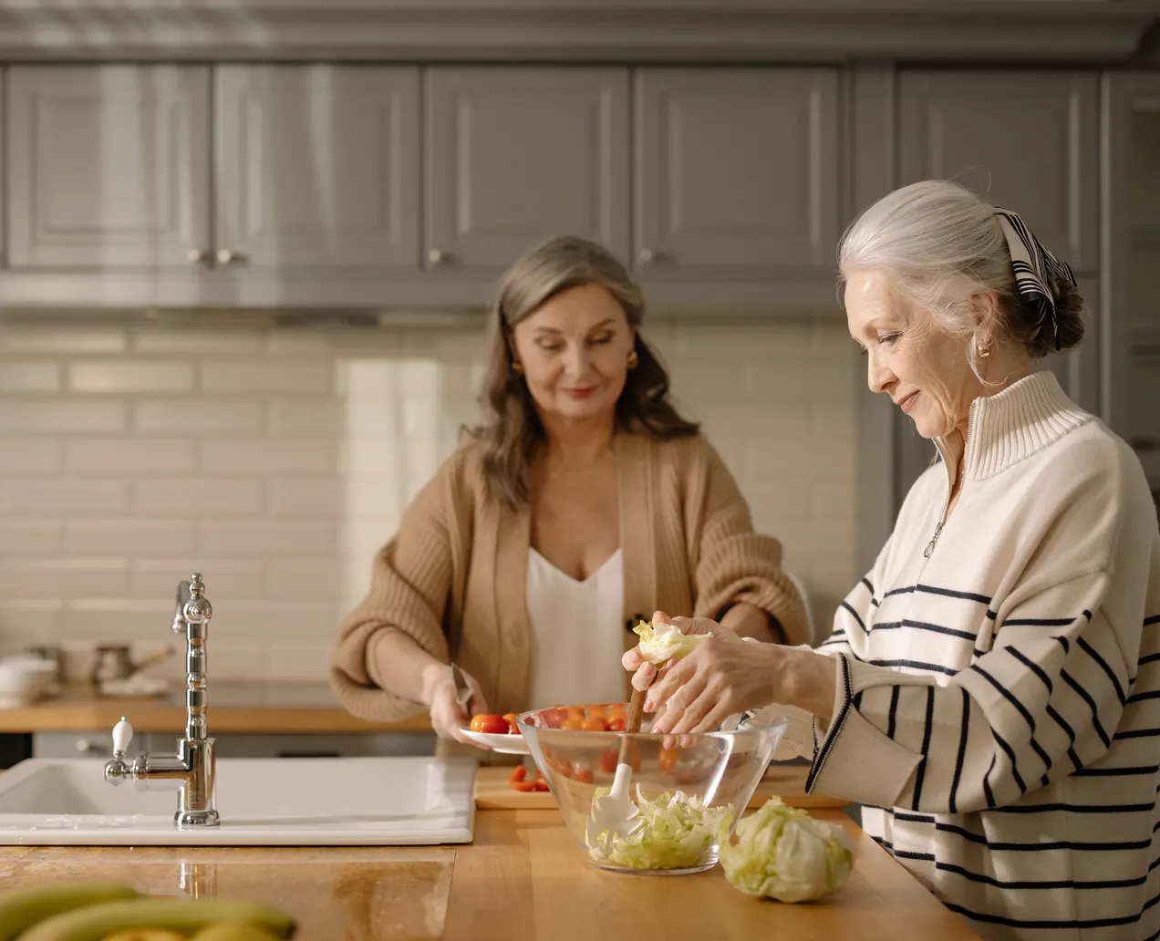 Due donne preparano il pranzo insieme al piano della cucina